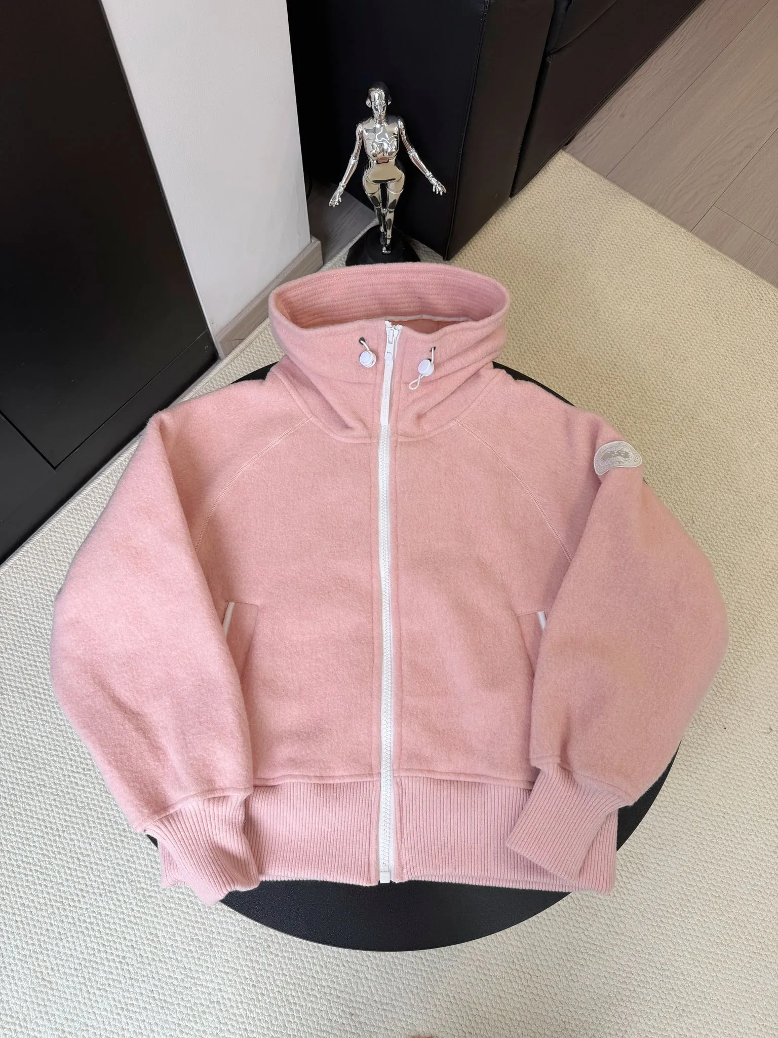 P660 Canada Goose Fleece Wool Badge Hooded Jacket Fabric selection: Wool fleece fabric blended with wool as the main body and a very small amount of spandex and polyester fiber. Wool is a core natural ingredient that provides unparalleled temperature regulation, antibacterial and anti-odor properties and a skin-friendly feel. The feeding of a small amount of spandex gives the fabric a certain degree of four-way elasticity, making it non-restrictive during daily activities. As the basis of fleece's structure, polyester fiber enhances the fabric's durability, wrinkle resistance and quick-drying properties. It contributes to the loft of the fleece and provides functions such as trapping air.  Detail 1: The sleeves and hem are closed with 2×2 ribbing. Its strong elasticity can closely fit wrists and waists of different thicknesses, forming an effective 'seal' to prevent cold wind from blowing back. It can still maintain its original shape after repeated stretching and use, and is not easy to loose and deform. And the ribbed cuffs can convey a sense of design and enhance the visual beauty.  Detail 2: The combination of hood design and elastic buckle improves warmth and windproof performance when wearing. Accessories: Customized elastic drawstring, elastic buckle, custom zipper pendant, custom armband Size: S M L Color: black gray coffee rice pink